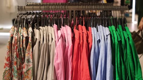 Customers Shopping in Apparel Store in Mall Big Variety of Colorful Shirts Hanging on the Shop Rails