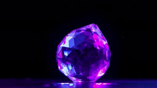 A Large Multi Faceted Diamond Rotates on a Black Background. The Facets of the Stone Shine and