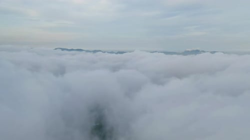 Aerial view of sunrise above fluffy sea fog misty clouds with mountain hill