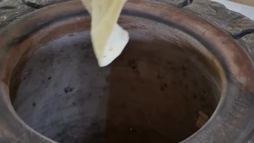 les mains d'un boulanger oriental sortent un mince lavash arménien cuit à Tonir à l'aide d'un