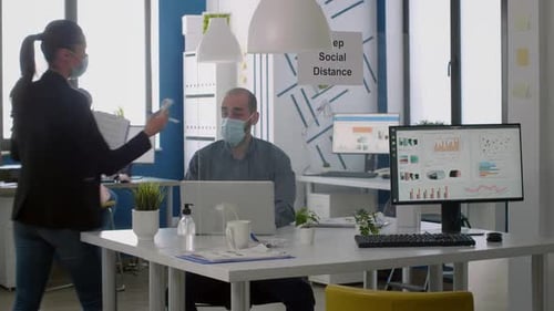 Freelancer with Protective Face Mask Checking Collegues Temperature with Thermometer