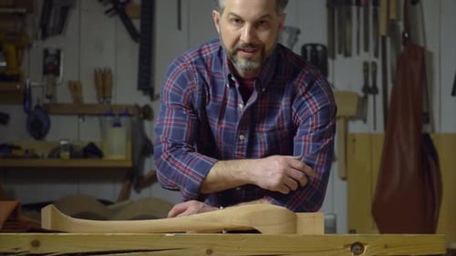 Man Smiles near Wooden Curved Object on Bench