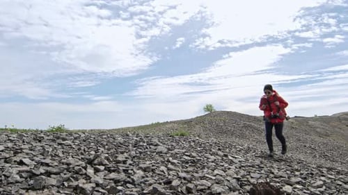 Woman Hiking Up Rocky Hill in Sunlight