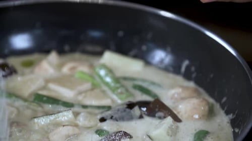 Adding Table Spoon of Salt Sugar from small Blue Bowl to Boiling Thai Vegetable Curry