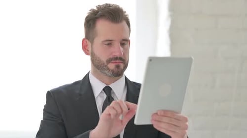 Young Businessman Celebrating on Tablet in Office