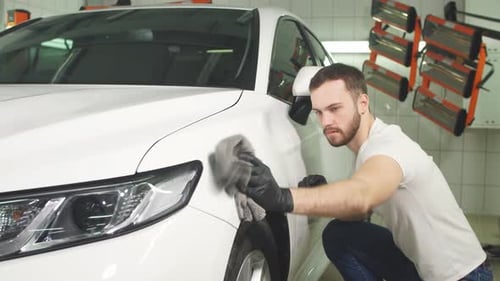 Man Detailing a White Car in Garage