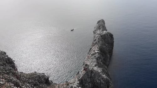 High cliff of a rocky mountain in sea with boat sailing around