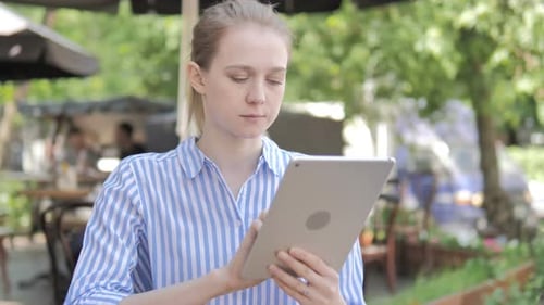 Young Woman Using Tablet Sitting in Cafe Terrace