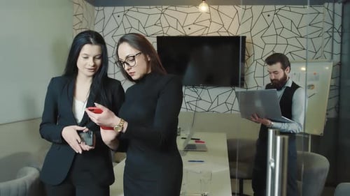 Two Girls in the Office During a Break Flaunt Mobile Phones and Social Networks