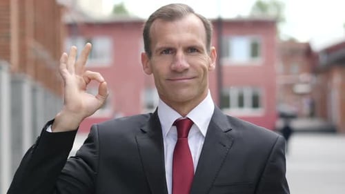 Smiling Man in Suit Gives Okay Hand Gesture