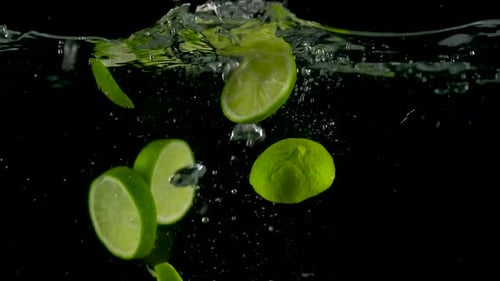 Limes Floating in Water on Black Background