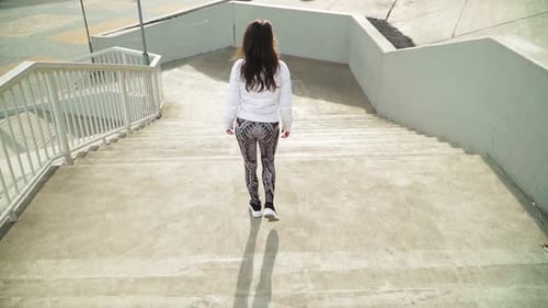 A young girl in a white jacket down the concrete stairs. Top view. Slow motion