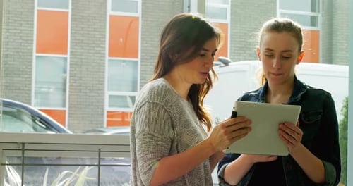 Two Women Looking at Tablet Indoors, Daytime