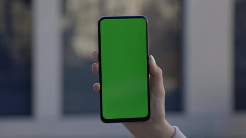 Businesswoman Holding and Touching Phone with Green Screen Vertically in Street