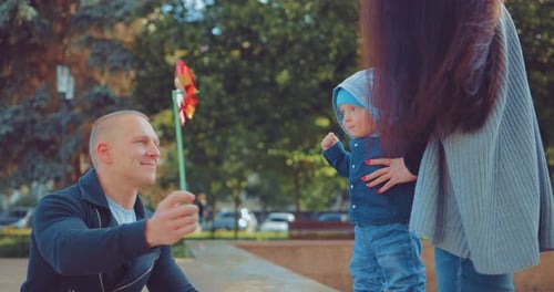 Happy Little Kid is Playing with His Parents in the Park