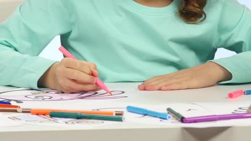 Niña pinta lápices con dibujos de animales. De cerca