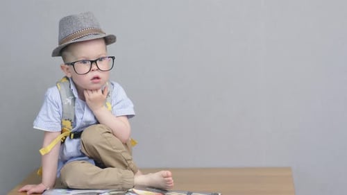 Porträt grübelndes nachdenkliches Kind im Vorschulalter, das in Hut und Brille sitzt