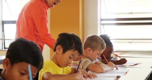 Teacher assisting school kids with their classwork in classroom