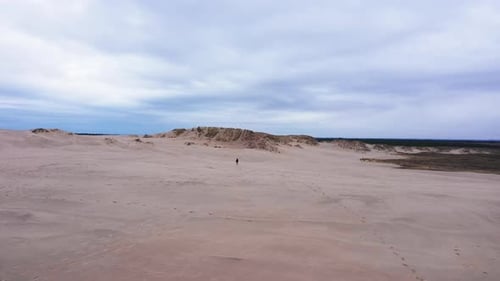Lone Figure Walks Across Vast Sand Dunes