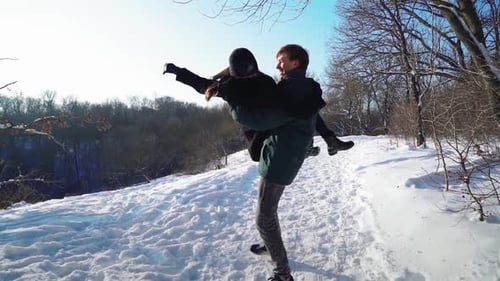 Un couple heureux passe du temps dans la forêt d'hiver à jouer et à jeter de la neige