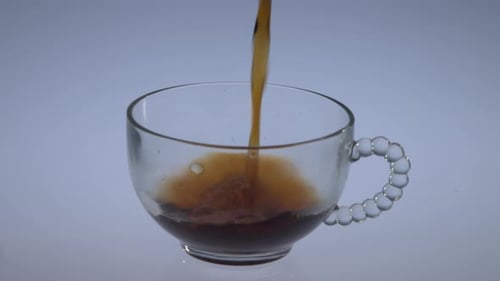 Pouring Dark Liquid into a Glass Cup