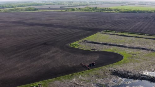 Aerial shot of tractor cultivating large unplanted field. Agricultural machines working in farmland