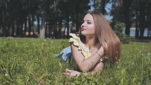 Ein schönes Mädchen posiert auf dem Gras im Park liegend