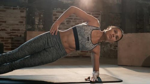 Fitness woman doing side plank exercise workout in gym indoors