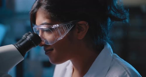 Female Research Scientist Looking Into Microscope,wearing Goggles, Close Up