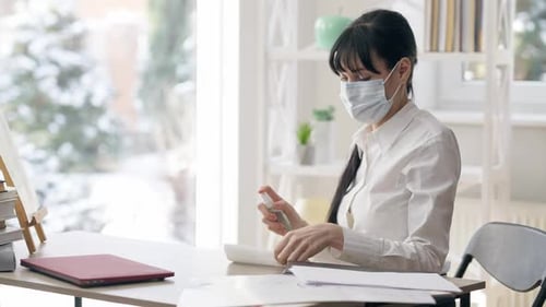 Woman Sanitizing Desk Surface with Spray and Towel