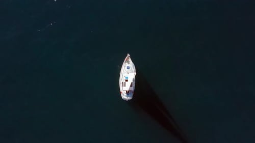 Segelboot segelt langsam auf eine untergehende Sonne im Mittelmeer zu.