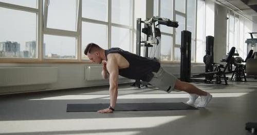 Young Muscular Athlete Works Out in a Modern Gym Making Push Ups Exercises