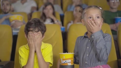 Frightened Middle Eastern Boy and Caucasian Girl Closing Eyes in Cinema. Portrait of Multiethnic