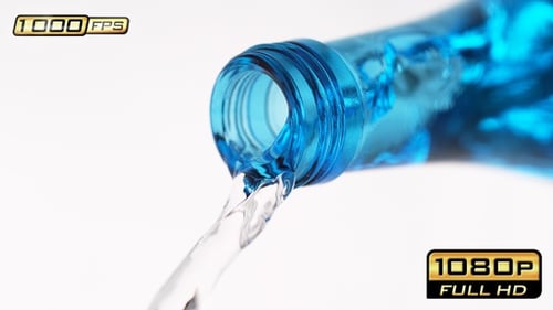 Water pouring from blue glass bottle close-up