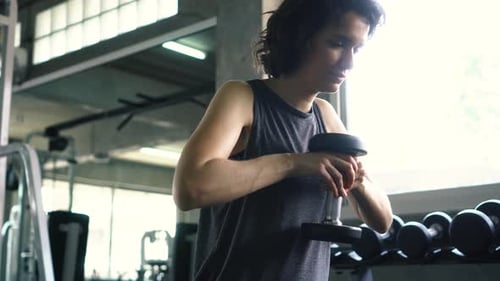 Fit Young Woman Exercising with Dumbbell at the Gym