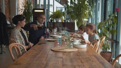 Family Dining at Restaurant with Greenery and Wine