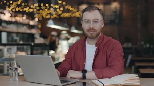 Portrait of the Student Man Looking at the Camera with Pleasure Smile in Cafe
