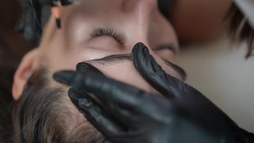 Woman Receiving Eyebrow Shaping Treatment in Beauty Salon
