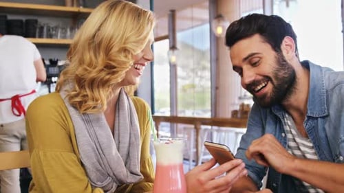 Couple looks at phone together in cafe