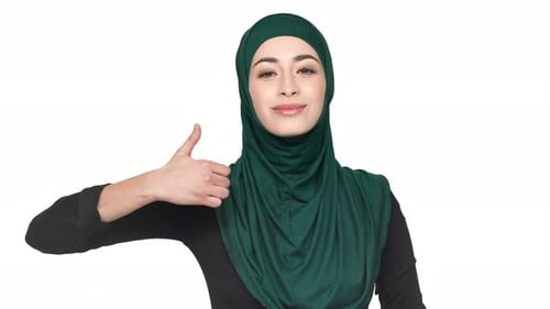 Porträt einer jungen religiösen Frau im traditionellen Niqab, die den Daumen nach oben zeigt und zufrieden ist