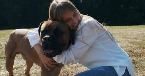 Smiling Woman Hugging Large Dog in Park