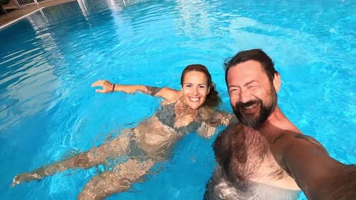 Happy caucasian people couple have fun and enjoy the swimming activity at the pool
