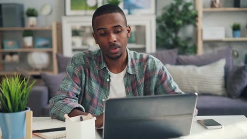 Man Working on Laptop at Table in Home Office