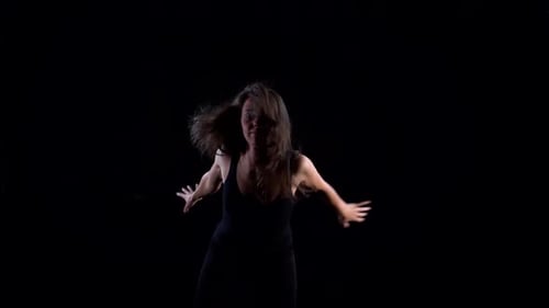 a Young Slender Woman in a Black Suit in a Studio on a Black Background Dancing, Moving and Posing.
