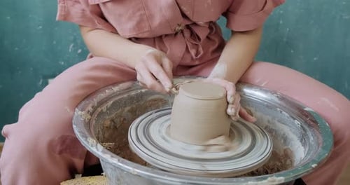 Female Potter Sitting and Makes a Cup on the Pottery Wheel. Woman Making Ceramic Item. Pottery
