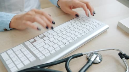 Close-up of Doctor's Hands Working with Computer Typing Sitting at Desk in Office