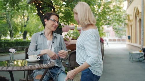 Friends Meeting in Street Cafe Hugging Looking Inside Paper Bags with Purchases