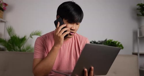 Young Adult on Phone with Laptop at Home