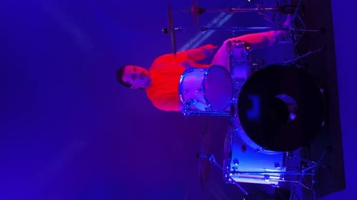 Cool Grunge Rock Musician Playing Drums on Stage, Doing an Amazing Metal Solo, Lit By Club Neon Red