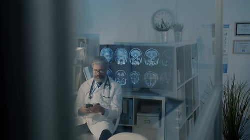 Male Doctor Using Smartphone in Office Then Meeting Female Colleague Looking at MRI Scans in Dark